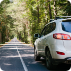 An SUV drives down a country road. 